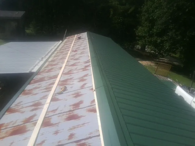 Old rusted panels beside newly installed green metal roofing — Wind Damage Roof Repair by Roofing Brothers in Lincoln
